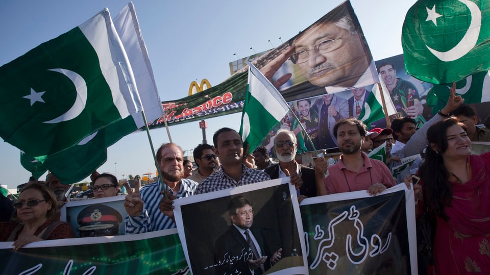 Anhänger von Pervez Musharraf halten pakistanische Fahnen und Bilder von Musharraf hoch