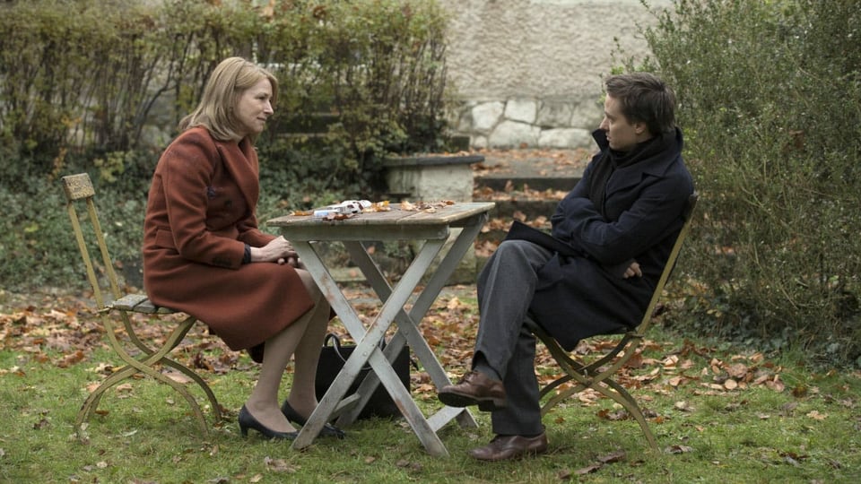 Filmstill: Eine Frau und ein Mann sitzen an einem Gartentisch.