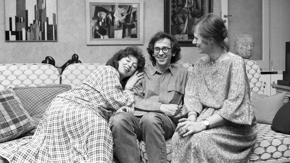Zwei Frauen und ein Mann lachend auf einem Sofa.