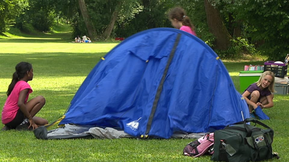 Mädchen helfen einander an allen Ecken beim Aufstellen eines Iglu-Zeltes.