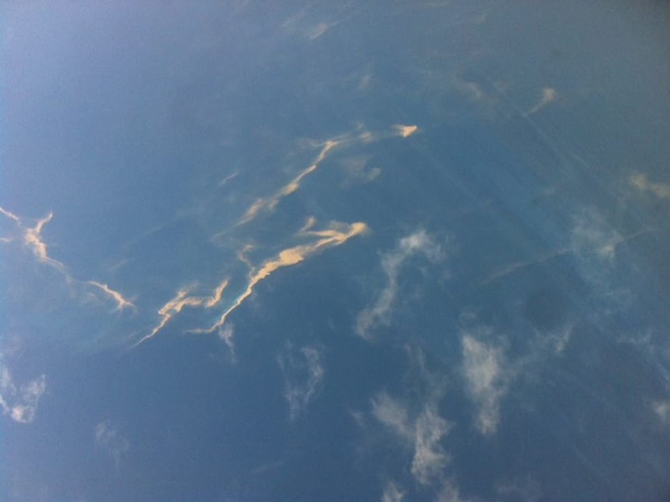 Schillernde Ölspur auf dem Meer vom Flugzeug aus gesehen.
