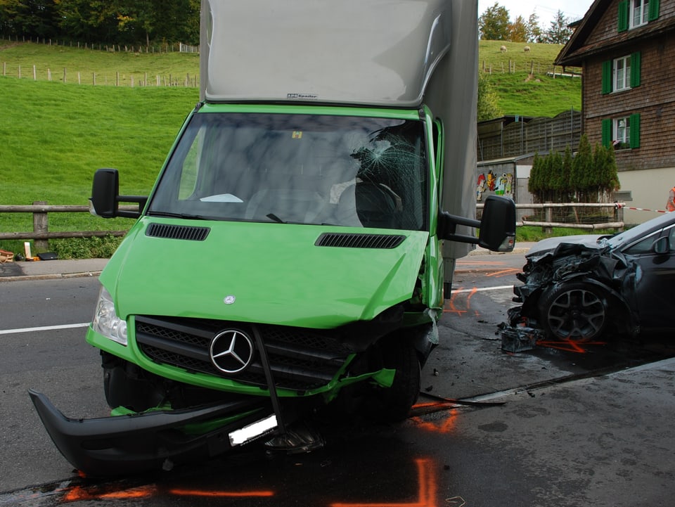 Ein grüner, kaputter Lieferwagen nach einem Frontalunfall.