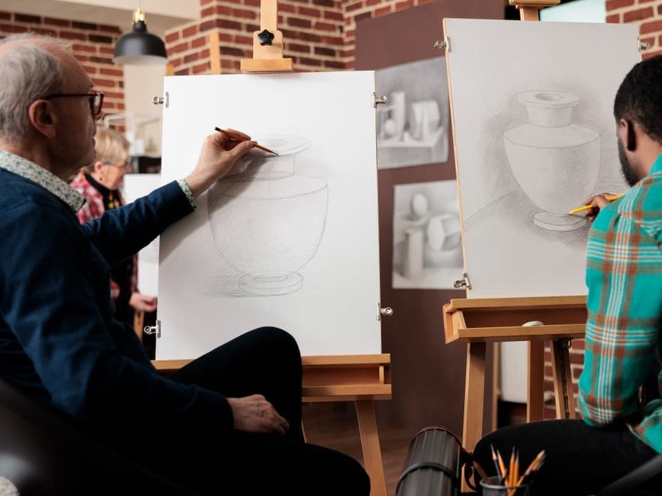 Zwei Männer sitzen in einem Studio, vor ihnen je eine Staffelei. Sie zeichnen Vasen mit Bleistift