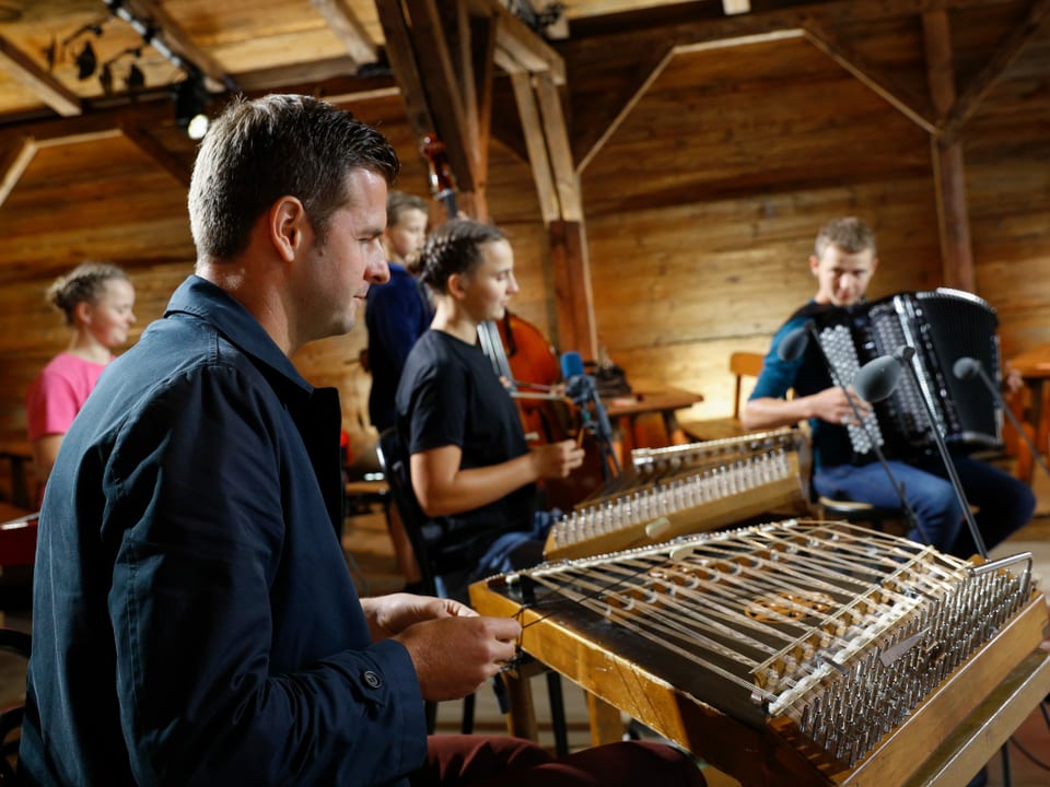 Nicolas Senn spielt Hackbrett mit jungen Musikerinnen und Musikern.