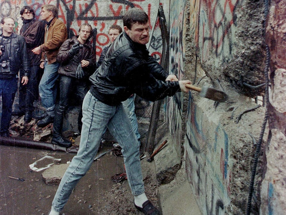 Ein Westdeutscher schlägt mit einem Vorschlaghammer auf die Berliner Mauer ein, im November 1989.