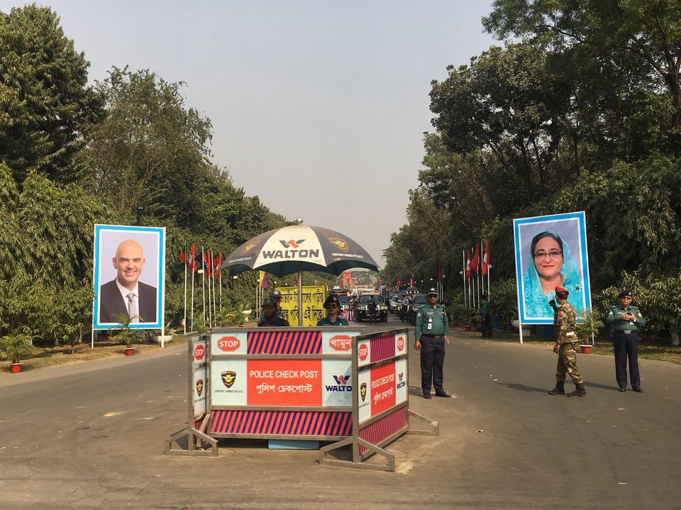 Eine Strassenkreuzung in Bangladesch zeigt links ein Plakat mit dem Bild von Alain Berset und rechts mit Scheich Hasina Wajed, Premierministerin des Landes. (srf)