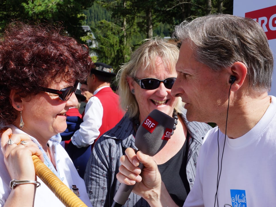 Tschümperlin trägt Mikrophon und In-Ear Kopfhörer während er die beiden Damen interviewt.