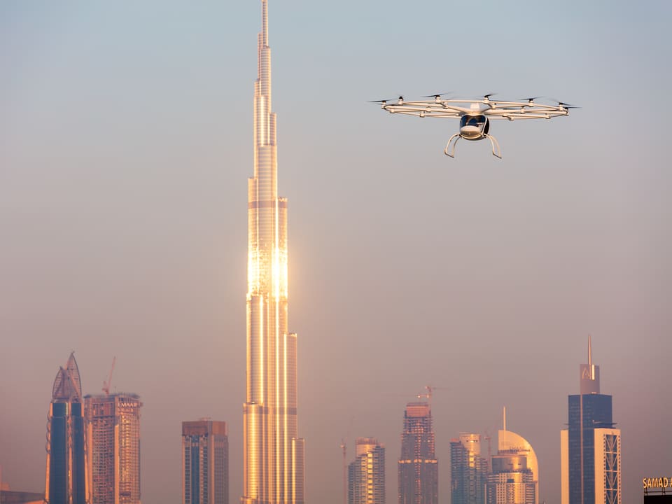 Volocopter fliegt vor einem Hochhaus in Dubai vorbei.