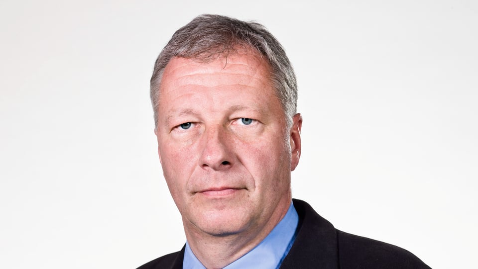 Fredy Gsteiger in einem Anzug vor einem hellen Hintergrund.