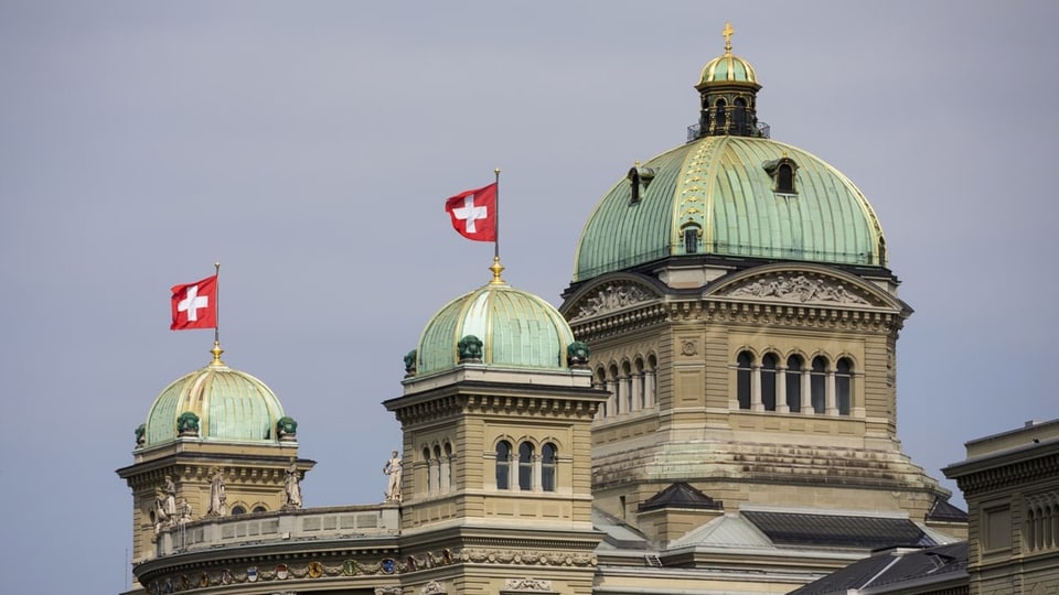 Das Bundeshaus in Bern mit zwei Schweizer Fahnen.