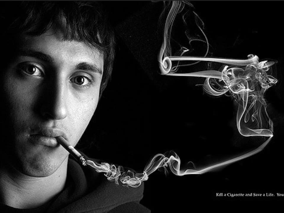 Rauchender Mann, neben seinem Gesicht eine Pistole aus Rauch. 