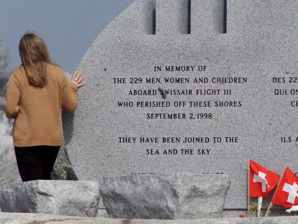 Eine Frau steht beim Gedenkstein.