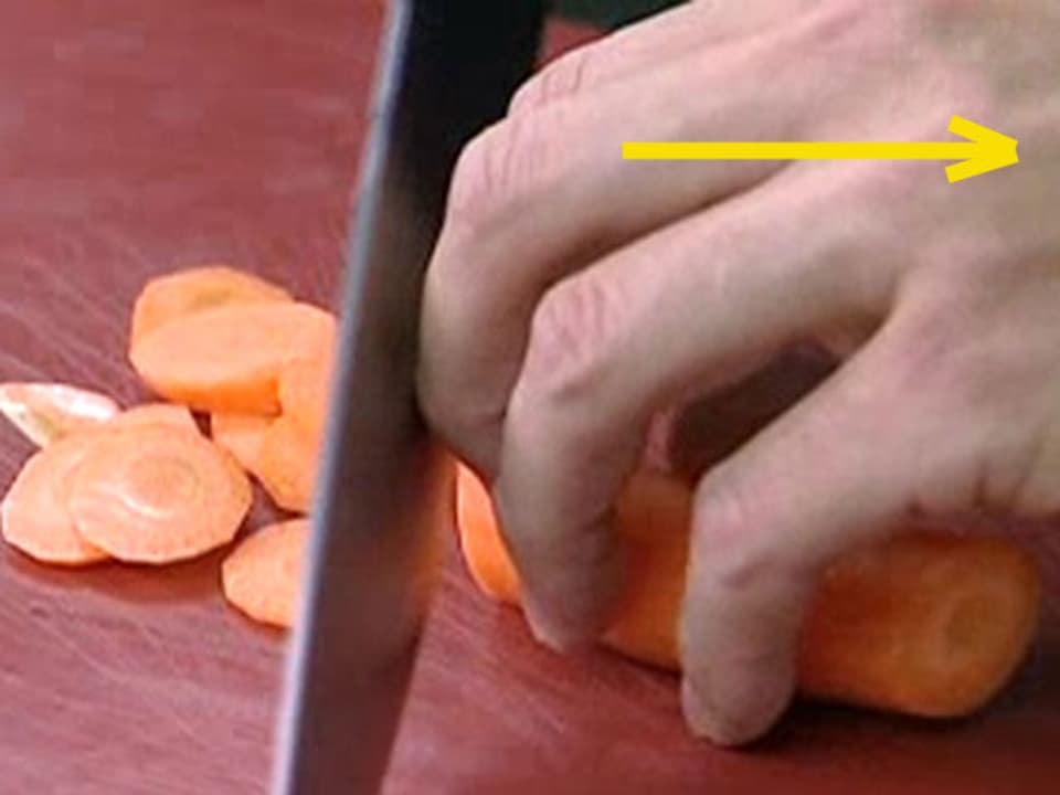 Mann schneidet Karotten in Scheiben.