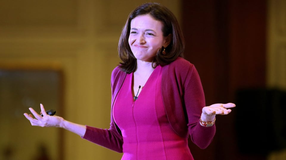 Sheryl Sandberg in pinkem Overteil und fragender Geste