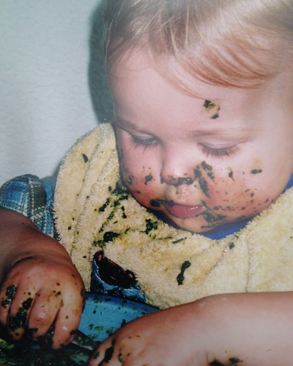 Ein Kind isst Spinat.