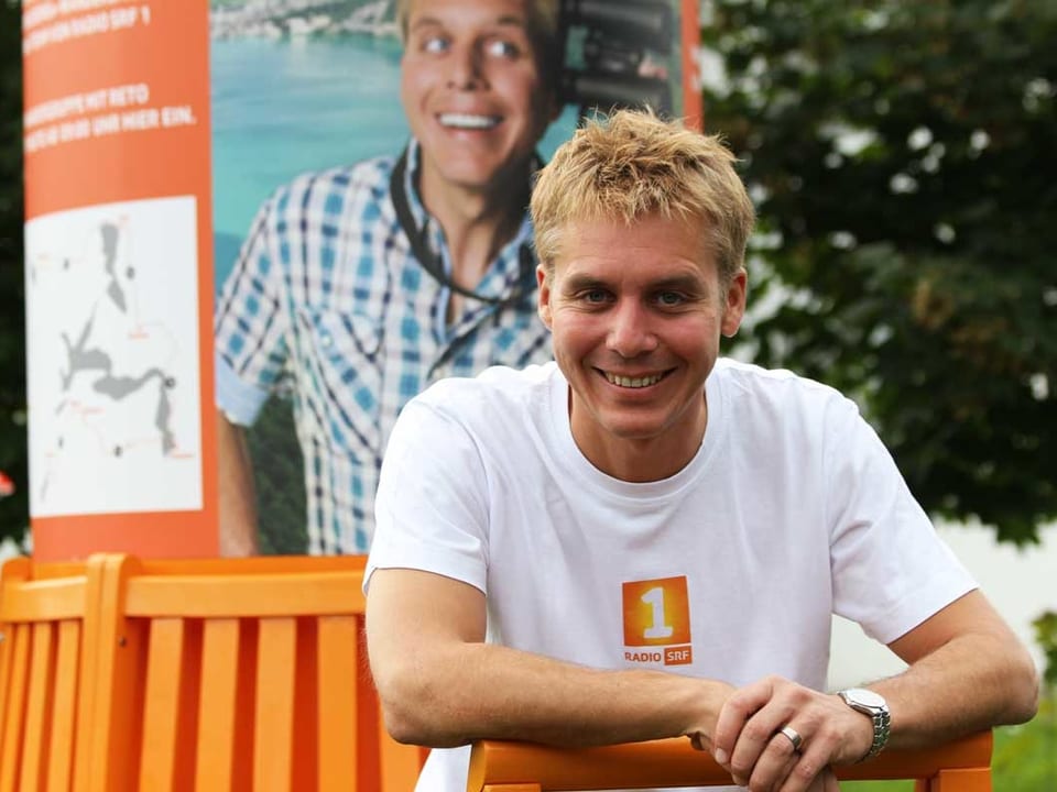 Porträt von Reto Scherrer auf dem orangen Wanderbänkli.