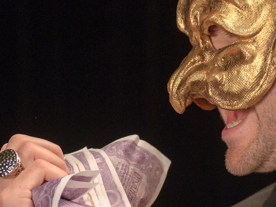 Mann mit goldener Maske und Geldscheinen in den Händen