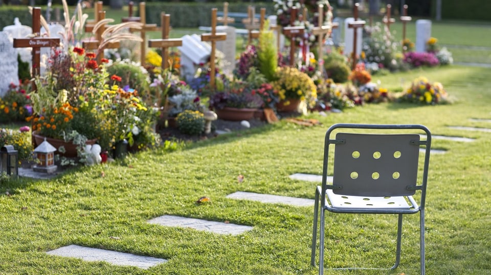 Ein Gartenstuhl auf einem Friedhof.