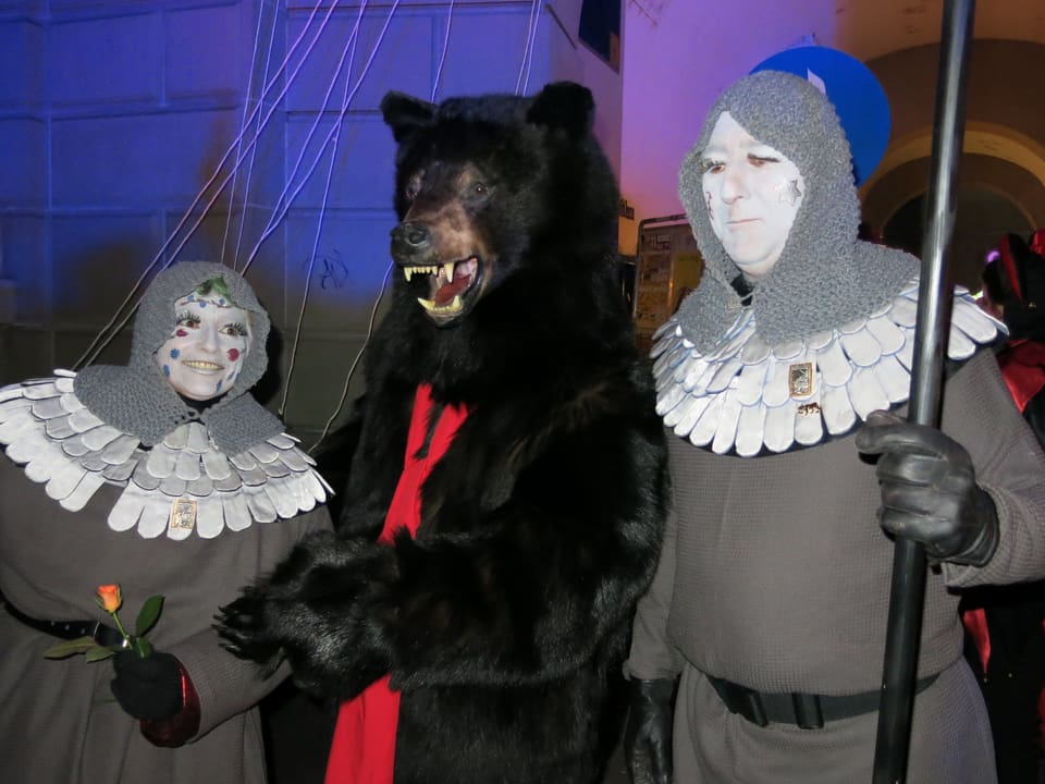 Der Bär mit zwei Bodyguards in Kostümen.