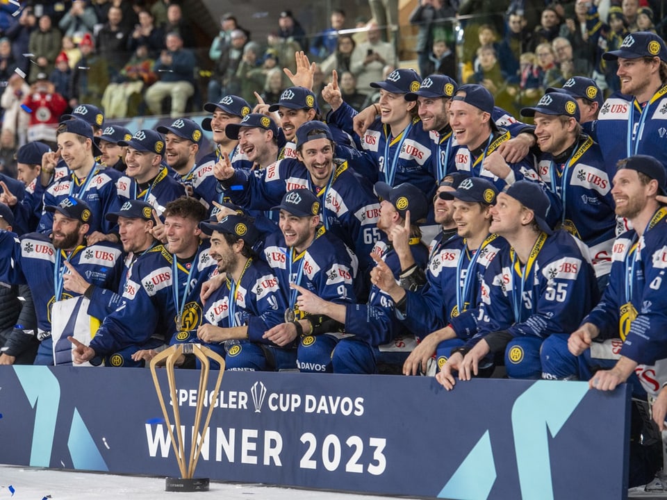Die Spieler des HC Davos posieren mit der Spengler-Cup-Trophäe.