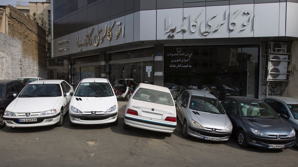 Vor einem iranischen Autogeschäft stehen verschiedene Peugeot-Modelle.