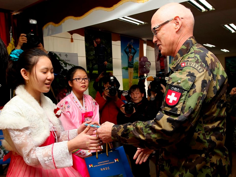 Ein Schweizer Soldat in Uniform wird von koreanischen Frauen begrüsst.