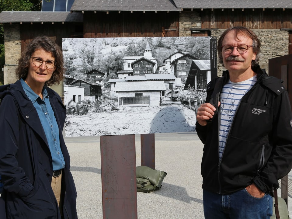 Zwei Personen stehen vor einem schwarzweissen Bild