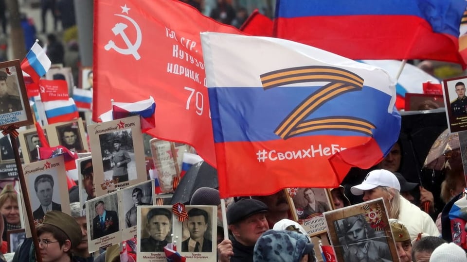 Protestierende mit einer Russland-Flagge mit dem orange-schwarz-gestreiften Z-Symbol.