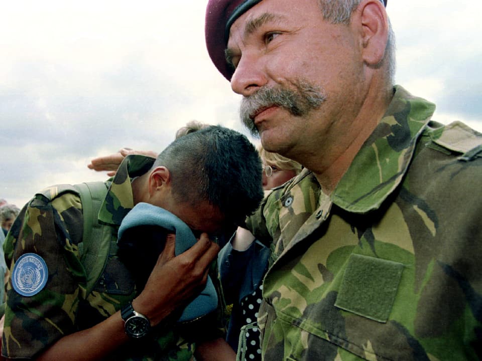Ein UNO-Blauhelmsoldatweint an der Schulter eines anderen Soldaten.
