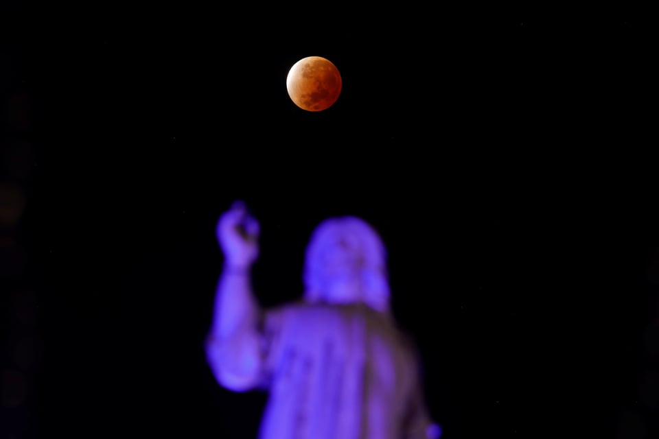 Mond scheint orange über Statue in El Salvador.
