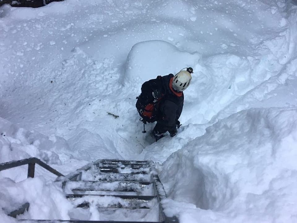 Metalleiter unten viel Schnee und ein Mann, der gerade runtergestiegen ist. 