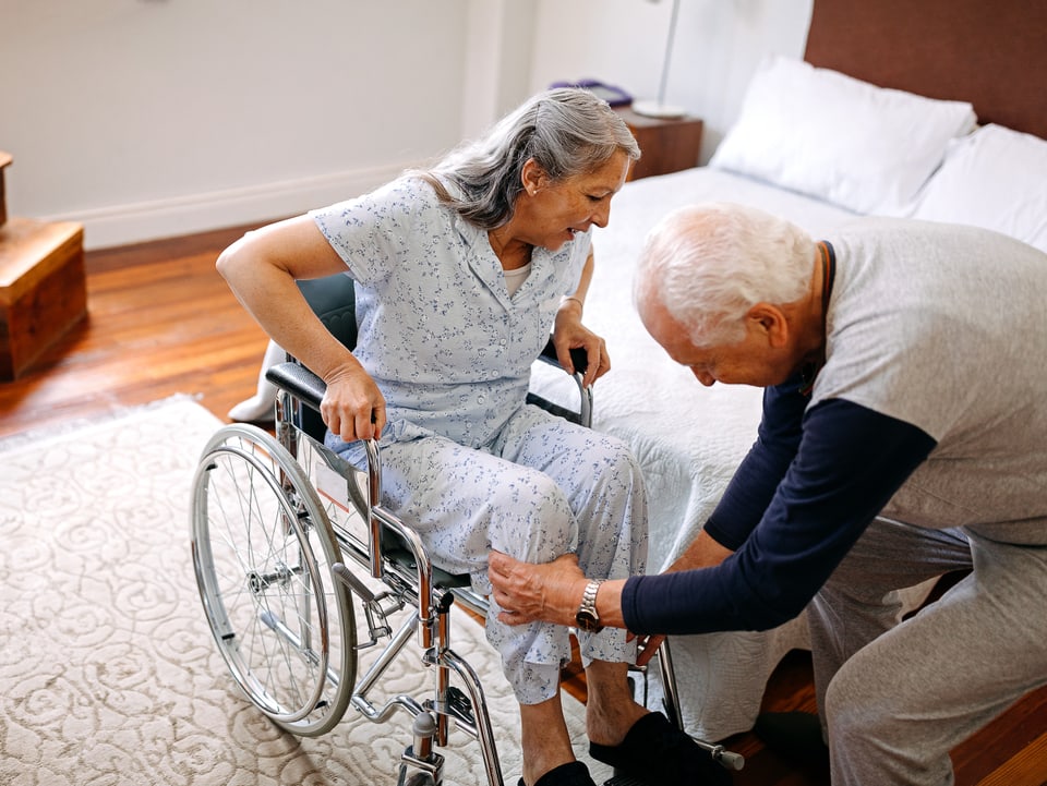 Senior hilft seiner Frau in den Rollstuhl