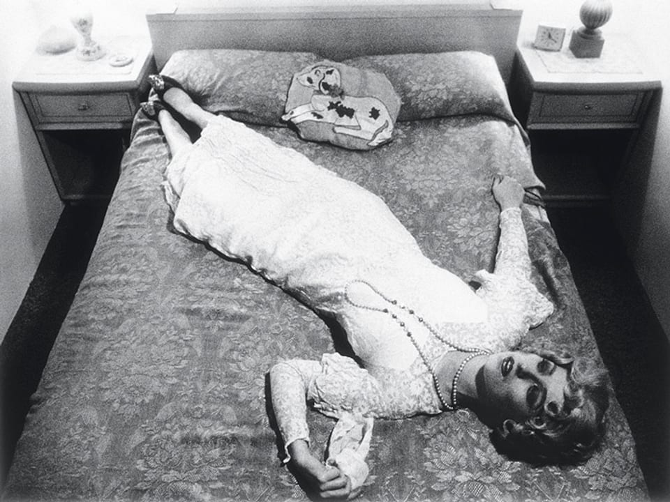 Eine Frau mit weissem Kleid liegt auf dem Bett.