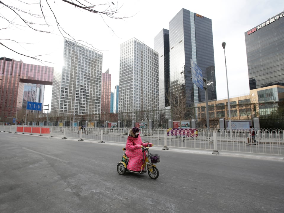 Frau fährt Motorrad in leerer Strasse in Peking