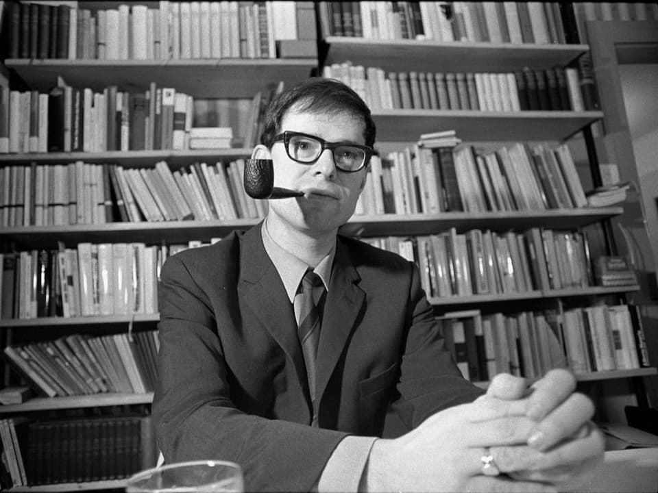 Herman Burger mit Pfeife vor einem Bücherregal