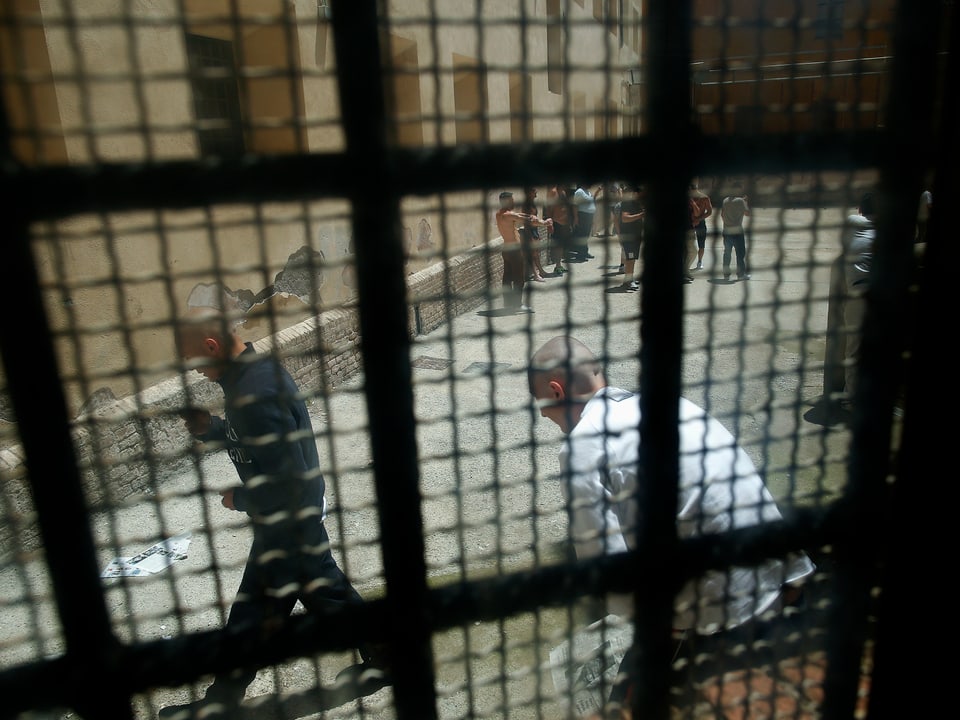 Blick durch Gitterstäbe auf einen Gefängnishof