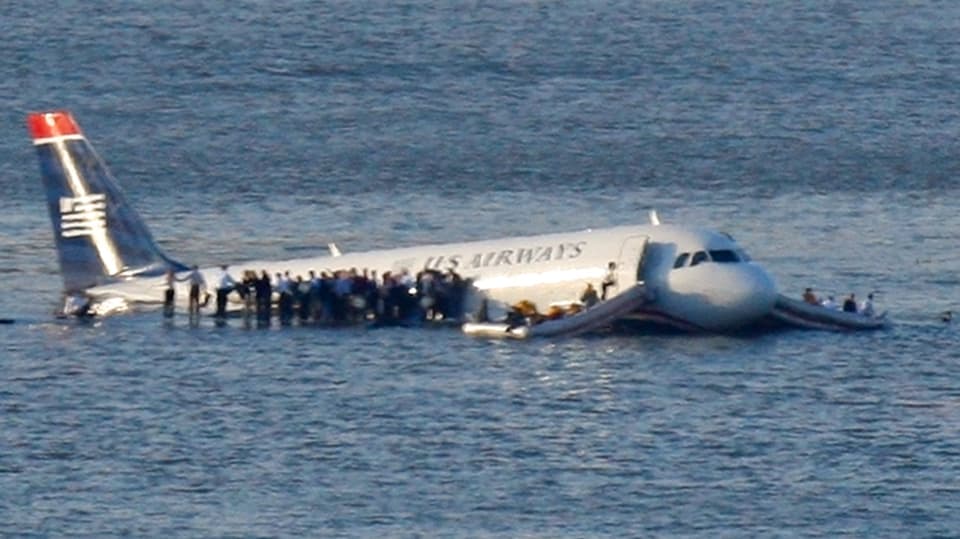 Passengers stand in the water after an emergency landing on the wings of an American Airlines plane