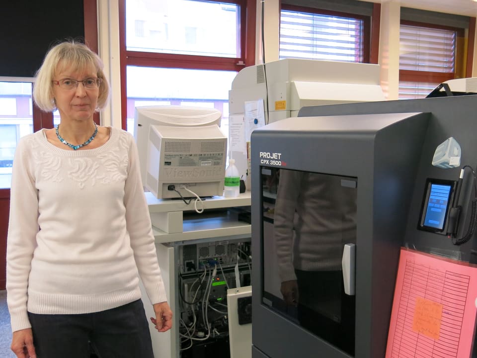 Bettina Steinmann steht neben einem 3D-Drucker.