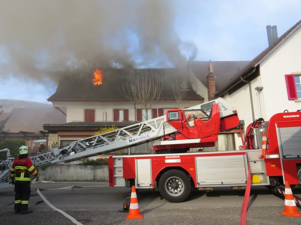 Drehleiter der Feuerwehr steht vor dem brennenden Haus