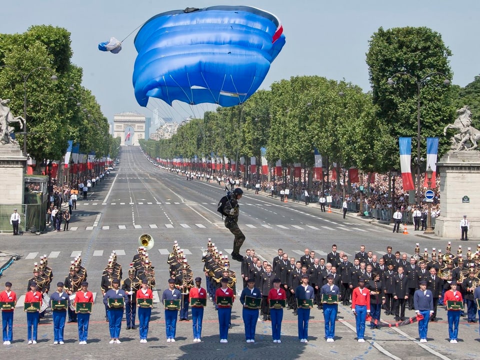 Ein Fallschirmspringer landet vor einer Militärparade zum Nationalfeiertag in Frankreich.