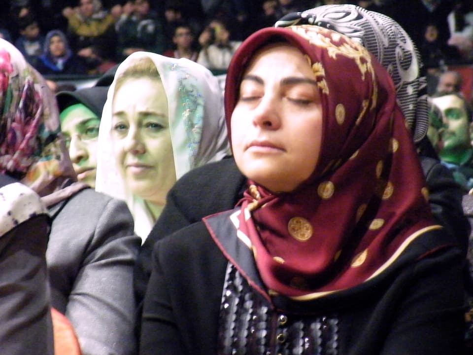Zwei Frauen in einer Menschenmenge hören konzentriert und bewegt zu.