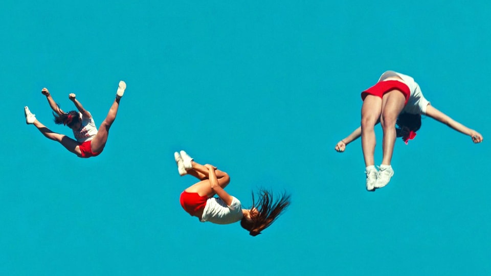 Drei identische Frauenfiguren fliegen durch die Luft.
