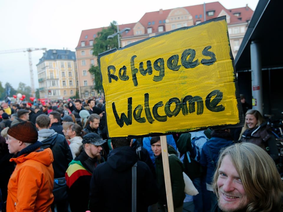 Gegendemonstranten in Dresden. Einer trägt ein Plakat mit der Aufschrift «Refugees welcome»