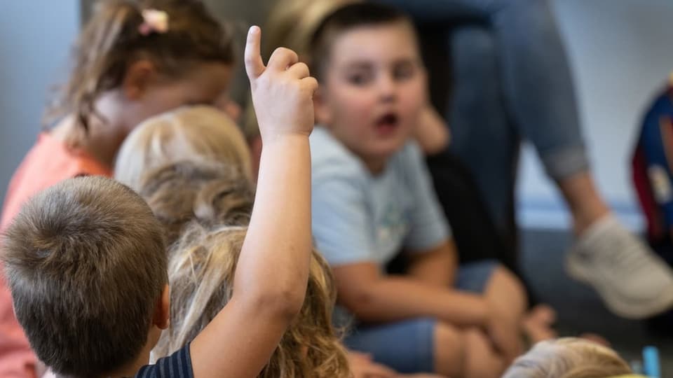 Kind streckt im Klassenzimmer den Arm in die Luft.