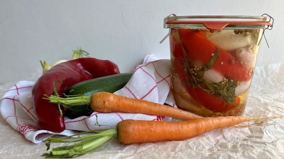 Ein grosses Weckglas mit Mixed Pickles. Gemüse als Deko.