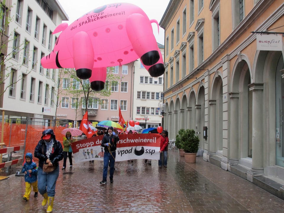 Ein bunter Umzug mit einem grossen, rosa Sparschwein als Luftballon marschiert durch die Schaffhauser Vorstadt.