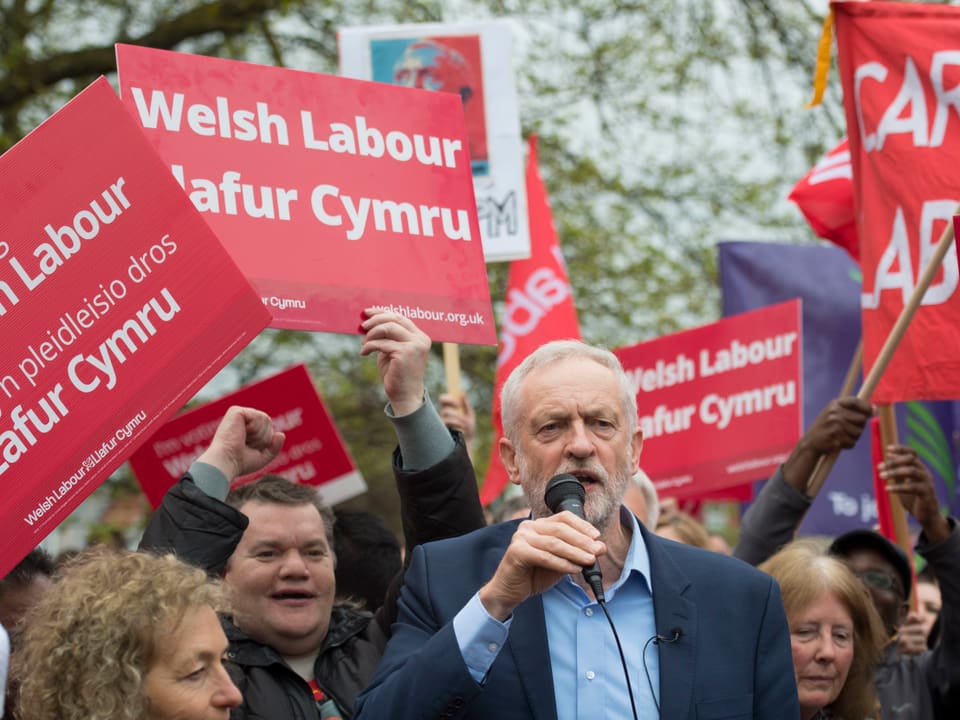 Corbyn spricht vor Anhängern in Wales, die rote Transparente mit der Aufschrift «Welsh Labour» hochhalten.