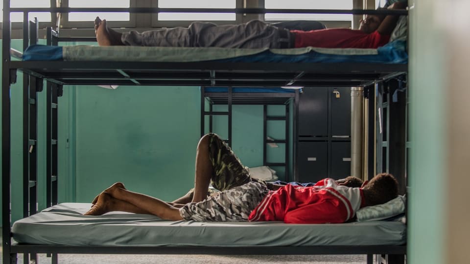 Asylsuchende auf Kajütenbetten.