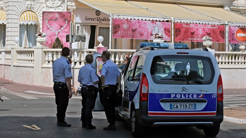 Polizisten stehen vor dem Hotel, an der Marquise Werbung für die Juwelen-Ausstellung.