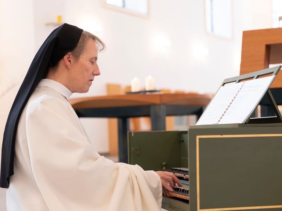 Eine Nonne spielt Klavier in der Kirche. 
